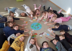 Dzieci leżą na podłodze i wskazują planetę Ziemię